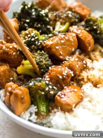 A bowl of Whole30 teriyaki chicken and broccoli with chopsticks in it.