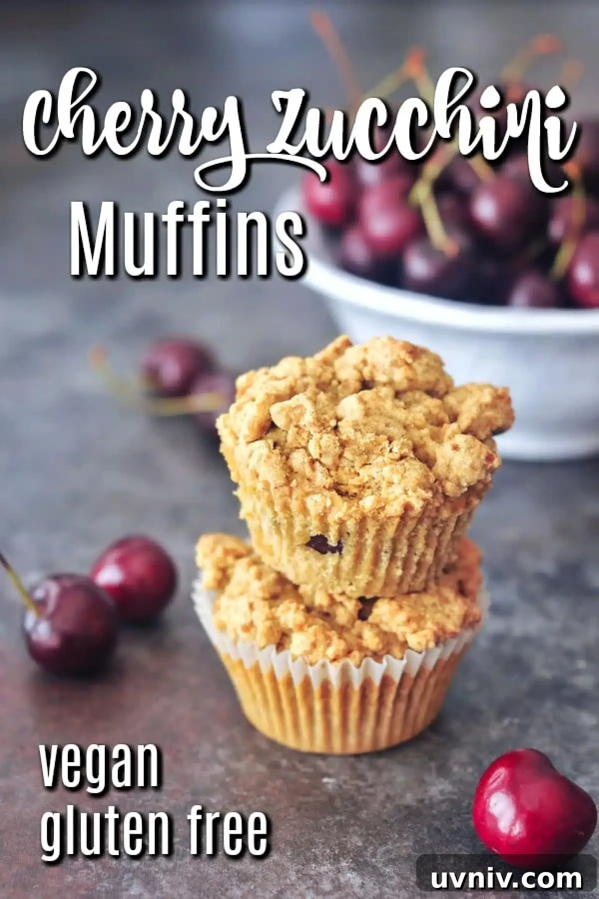 Cherry Zucchini Crumb Muffins @spabettie #glutenfree #vegan Two cherry zucchini muffins stacked one on top of another, with a bowl of fresh cherries in the background.