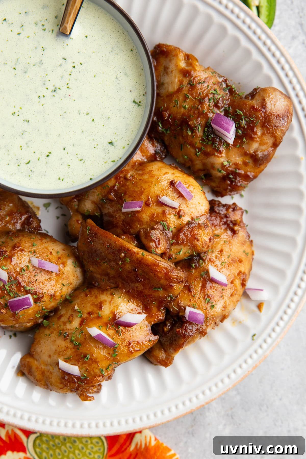 Peruvian Roast Chicken with Aji Verde Green Sauce Recipe 9 Peruvian chicken on a white plate with a bowl of green sauce to the side.