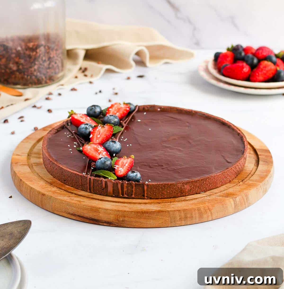 French Chocolate Ganache Tart Recipe: Rich, Silky Dessert Guide 7 Tart on a round wooden board over a white surface.