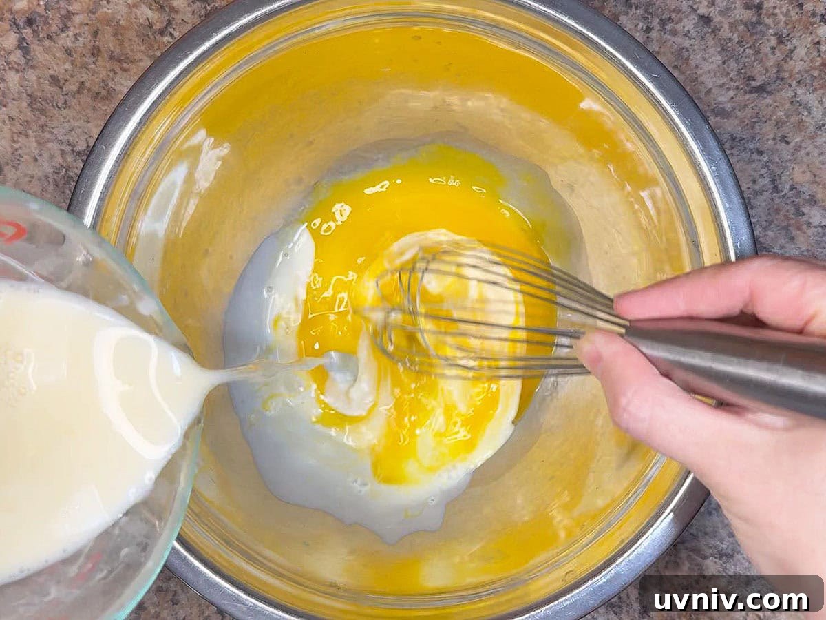 White Chocolate Cranberry Bread Pudding Recipe for Holidays 12 Tempering the mixture by adding warm cream to the egg yolks.