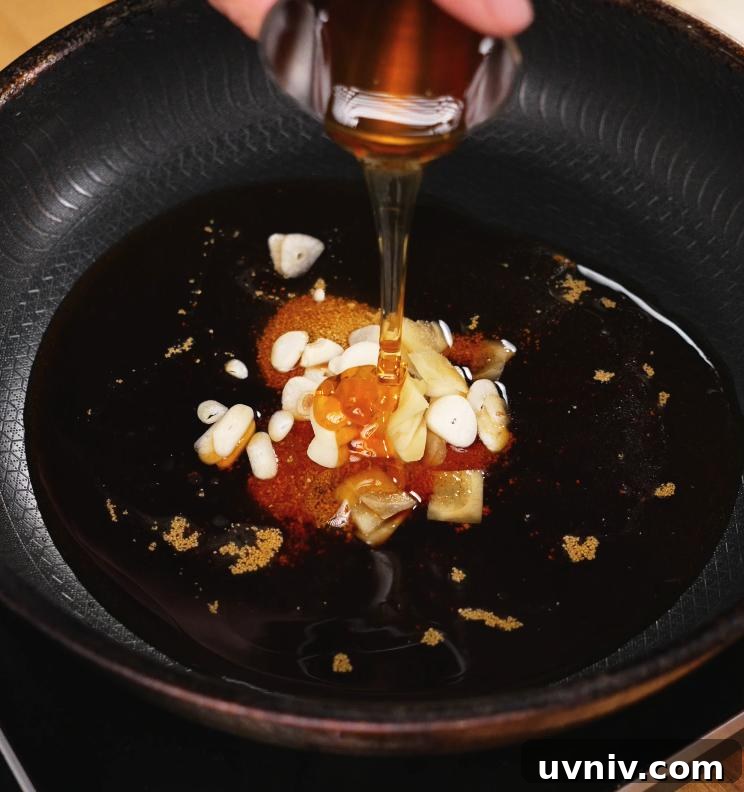 Ginger-Braised Chicken with Soy and Scallions Recipe 4 A glass container of honey is being poured into a pan containing garlic, ginger, and soy sauce, forming the rich and aromatic braising base for the chicken.