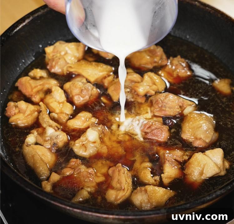 Ginger-Braised Chicken with Soy and Scallions Recipe 6 A cornstarch slurry is being poured into the simmering ginger soy chicken mixture, helping thicken the sauce to a glossy finish.