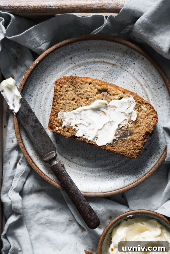 Irresistible Brown-Butter Banana Bread Recipe 4 Slice of banana bread smeared with butter on blue plate.
