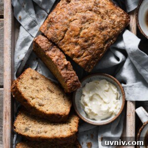 Irresistible Brown-Butter Banana Bread Recipe 5 Loaf of banana bread in a wooden tray next to a dish of butter.