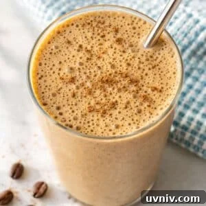 Coffee smoothie in tall glass with banana and soft natural light by window.