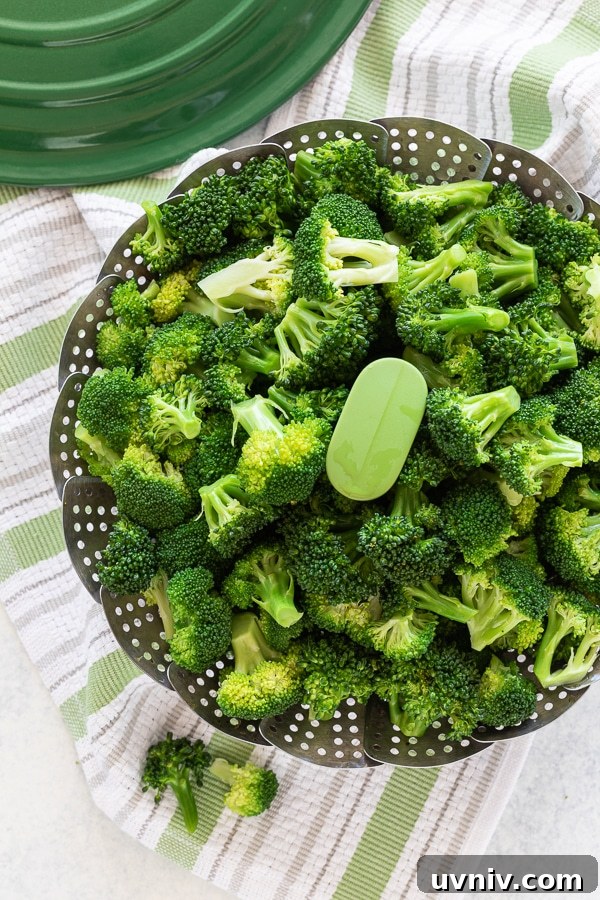 Bright green steamed broccoli florets in a steaming basket.