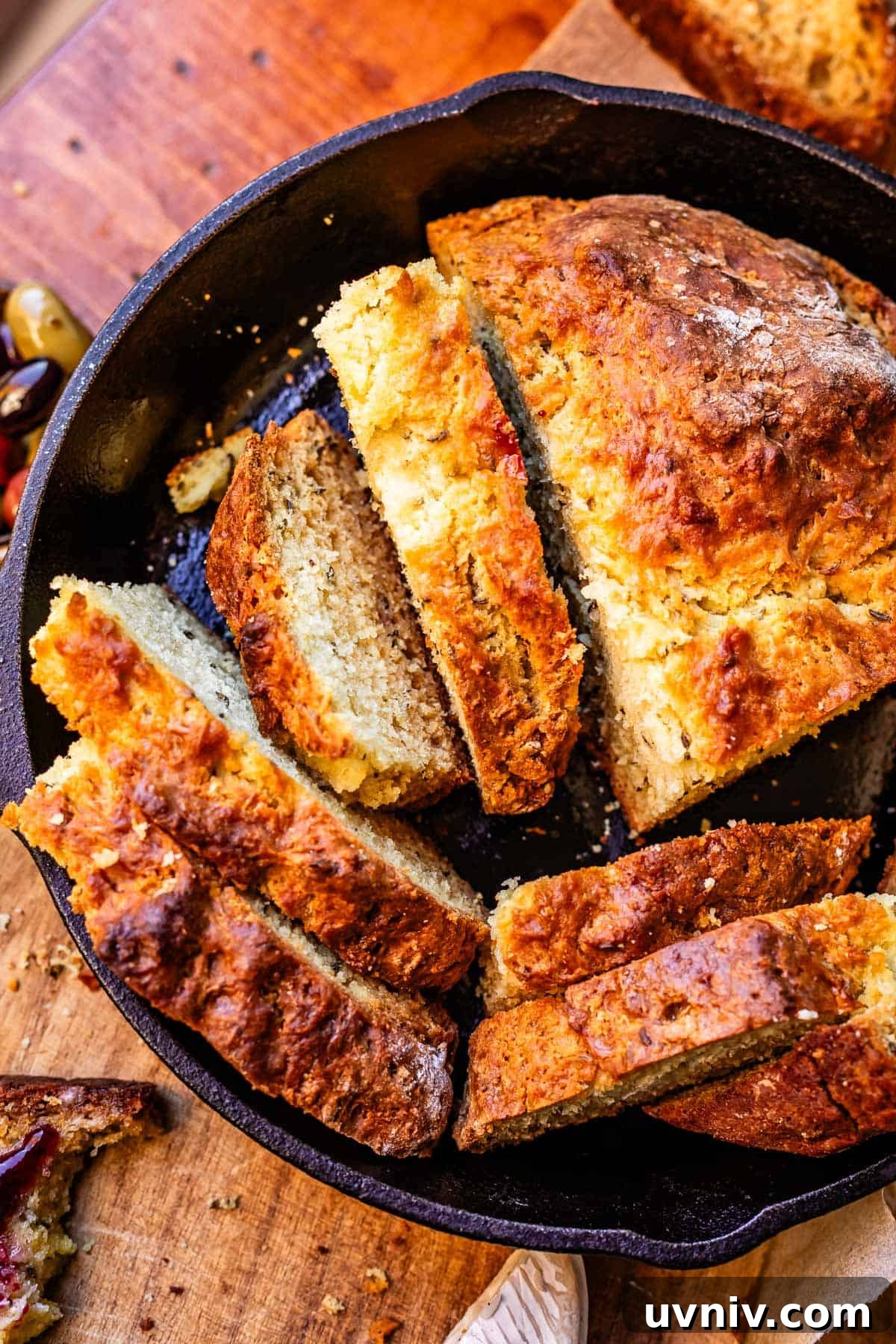 Authentic Irish Soda Bread Recipe You Can Make at Home 15 Overhead shot of loaf of Irish soda bread cut into many different slices sitting in cast iron skillet.