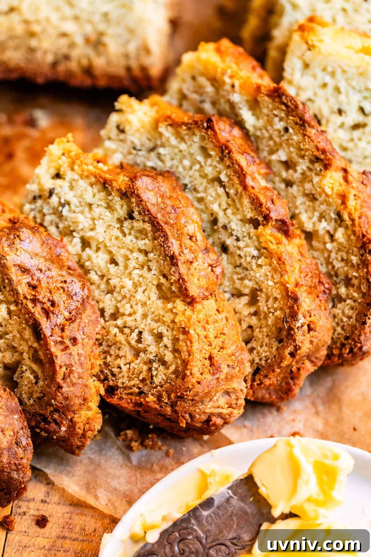 Authentic Irish Soda Bread Recipe You Can Make at Home 16 Slices of Irish soda bread nested over each other with butter in the foreground.