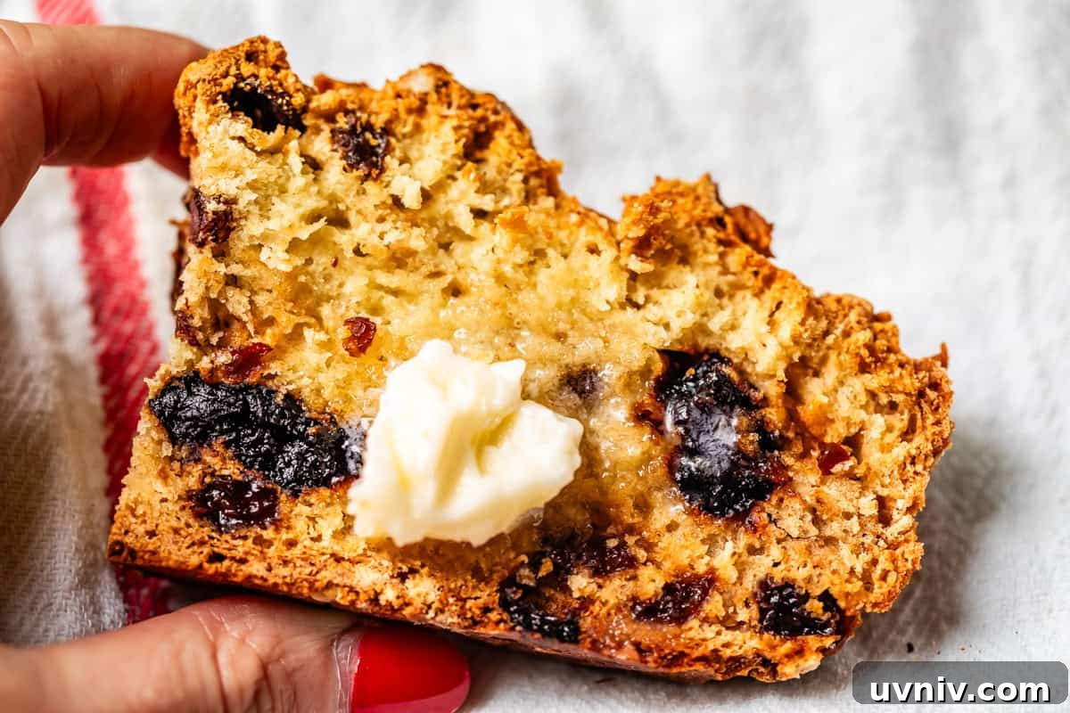 Authentic Irish Soda Bread Recipe You Can Make at Home 17 Close-up of soda bread showing baked-in cherries and raisin with pat of butter melting on the center.