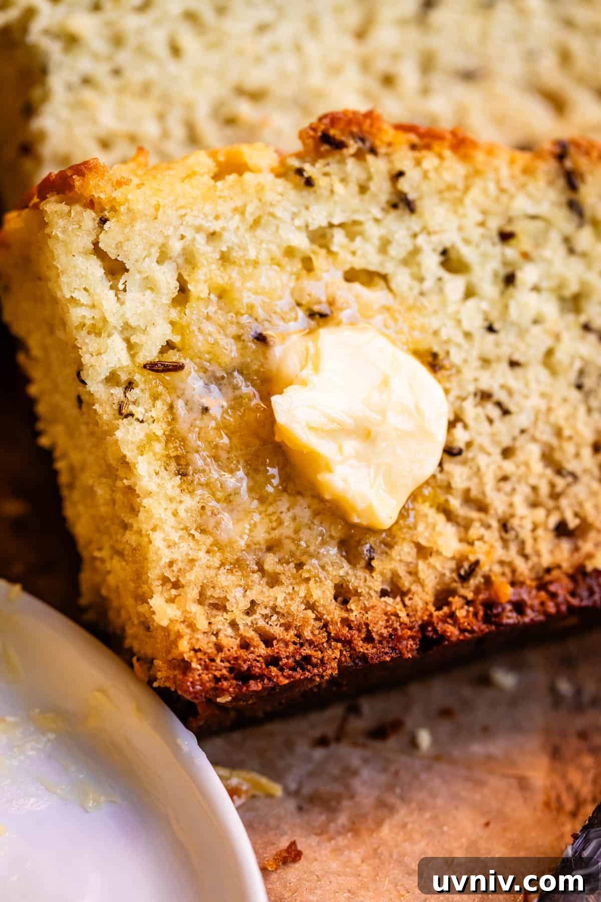 Authentic Irish Soda Bread Recipe You Can Make at Home 4 Close up of slice of Irish soda bread showing caraway seed with melting pat of butter.