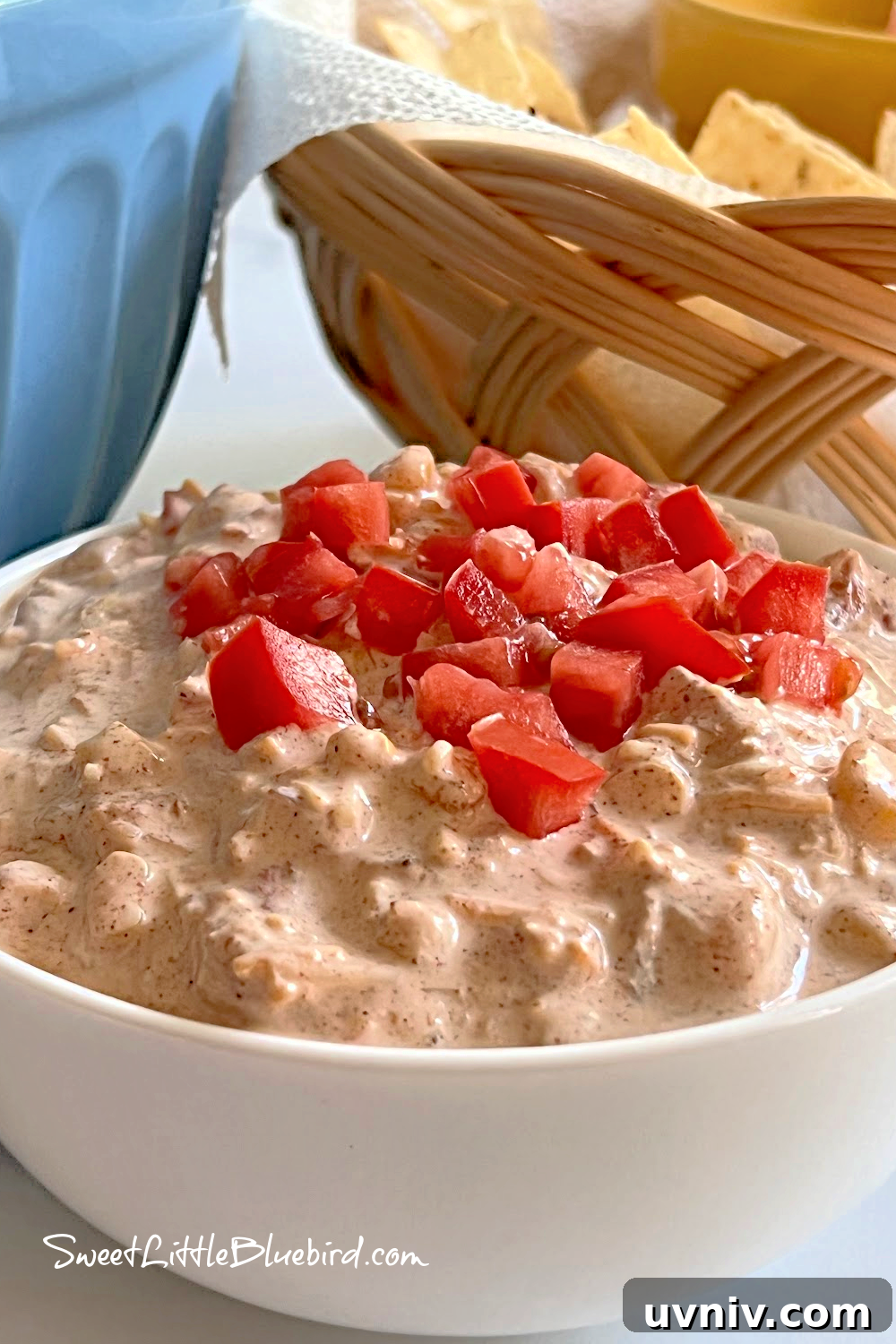 5-Ingredient Party Boat Dip Recipe for Quick Entertaining 6 This photo shows Boat Dip served in a white bowl with a few chopped tomatoes on top.
