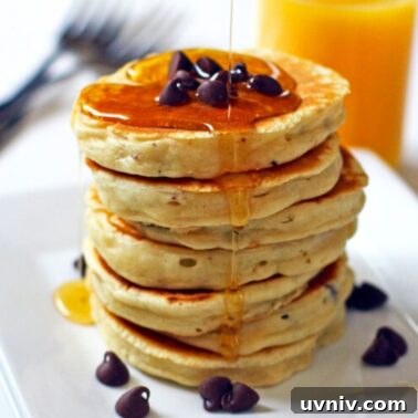 Irresistible Chocolate Chip Pancakes Recipe for Fluffy Stacks 5 A stack of chocolate chip pancakes with maple syrup on a white plate with a glass of orange juice in the background.