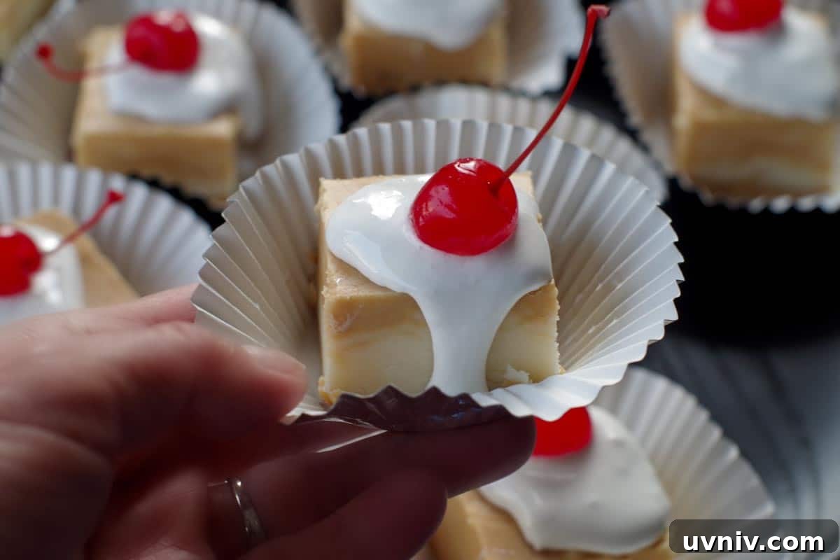 Root Beer Float Fudge Recipe: Creamy Soda-Infused Candy 3 a piece of root beer float fudge being held up in front of a tray of more root beer float fudge