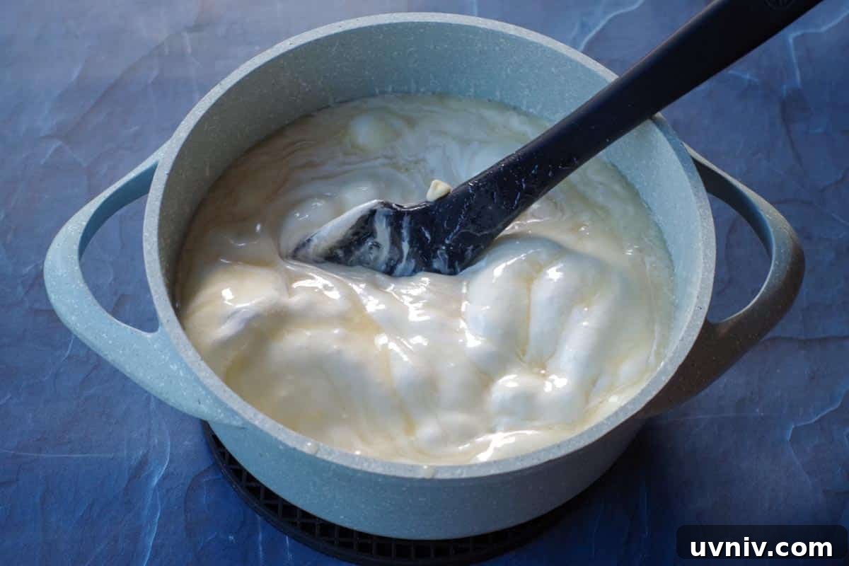 Root Beer Float Fudge Recipe: Creamy Soda-Infused Candy 9 white chocolate chips and marshmallow creme added to blue pot with sugar, milk and butter mixture