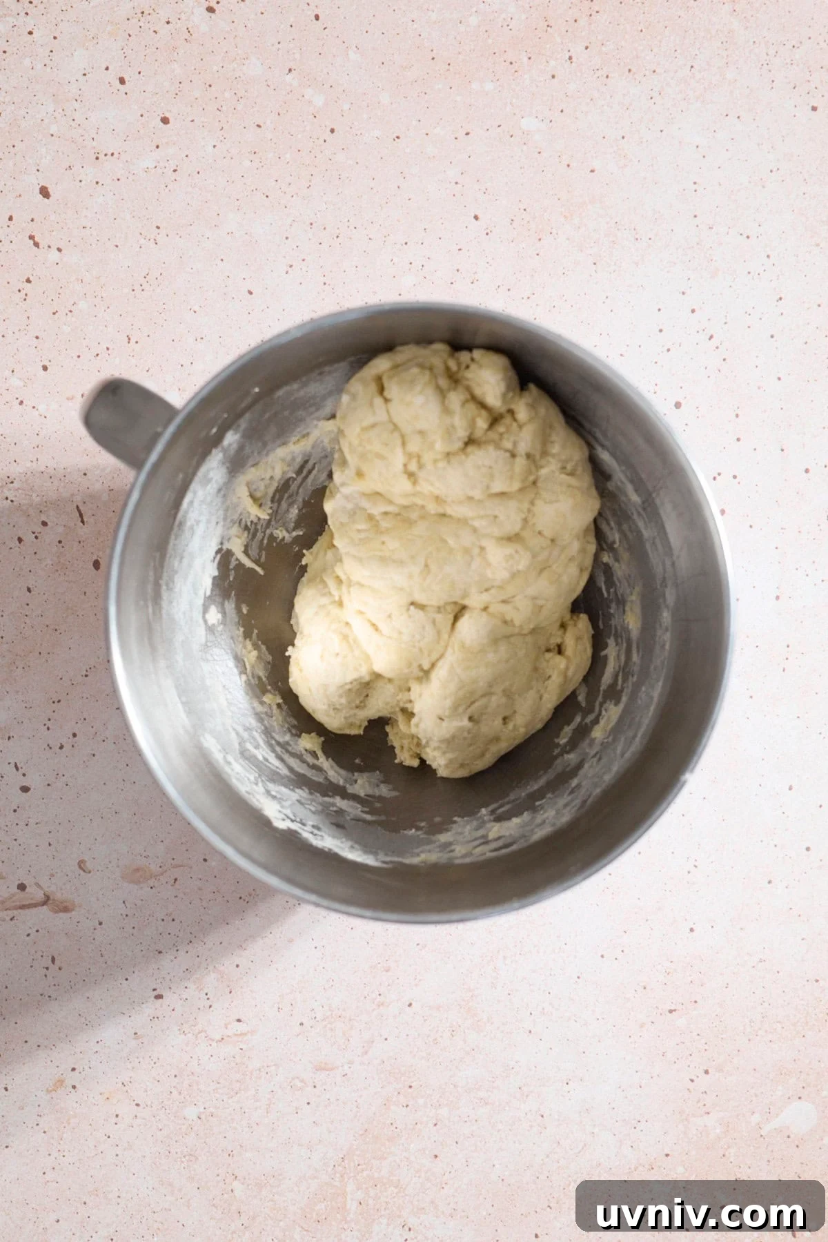 Shaggy dough in the bowl of a stand mixer.