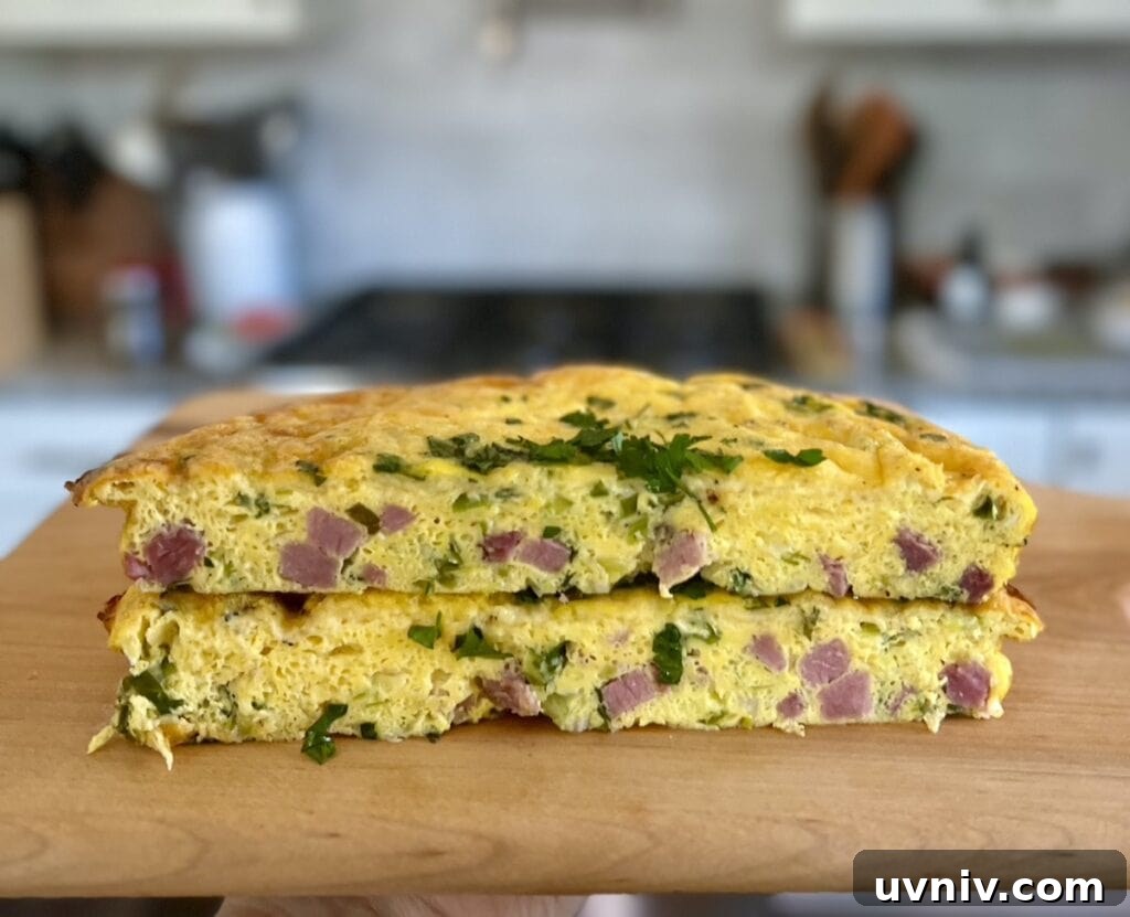 Two halves of easy ham and cheese frittata stacked on top of each other on cutting board.