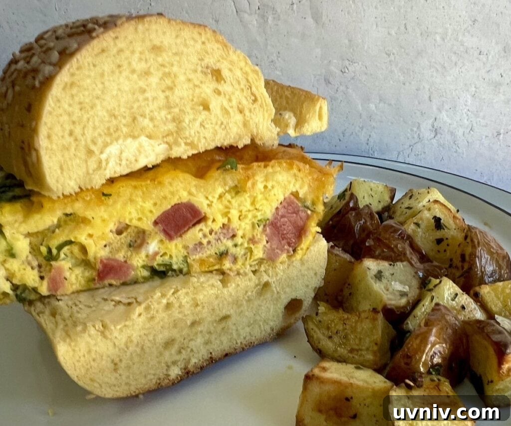 Cheese and ham frittata sandwich with roasted potatoes on plate.