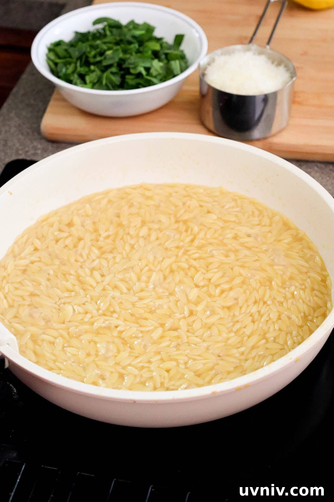 Cooked orzo in a large skillet with some liquid leftover.