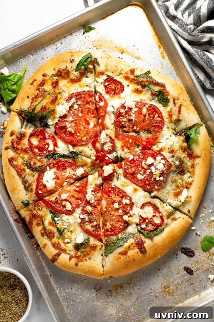 Overhead shot of a tomato pizza on a baking sheet with a hand reaching out for once of the pieces 