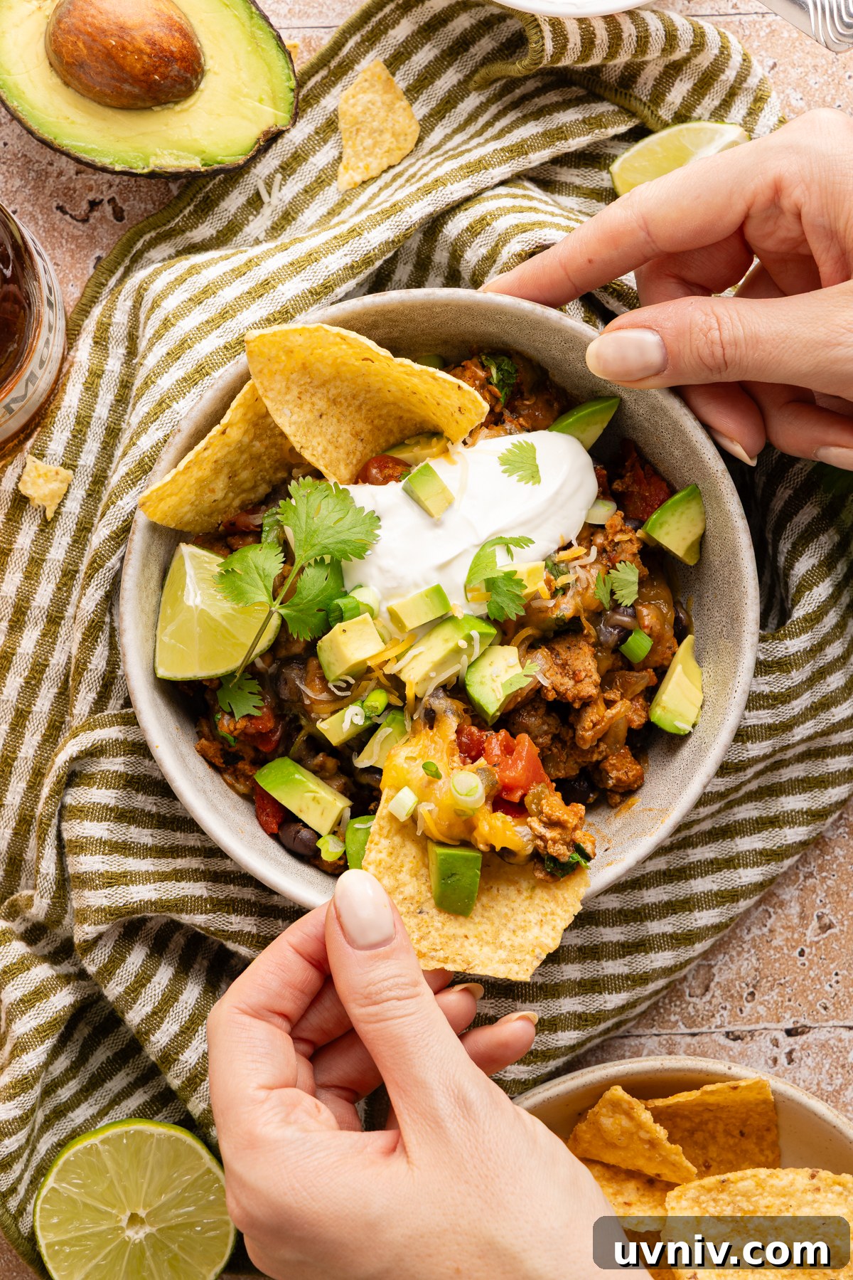 Cheesy Turkey Taco Skillet Dinner — One-Pan Weeknight Meal 12 A person digging a tortilla chip into a small serving bowl of cheesy turkey taco skillet
