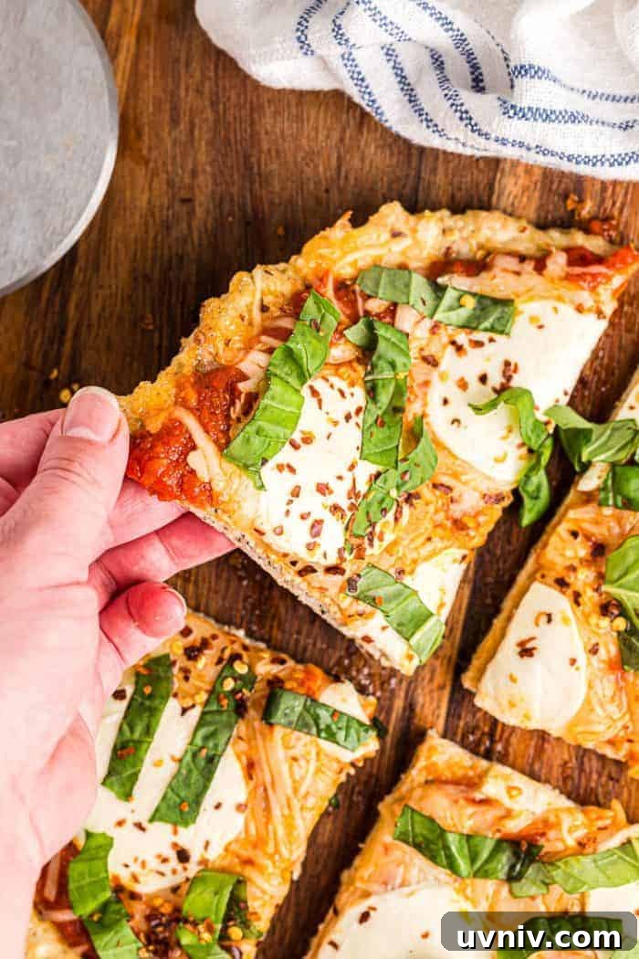 Low-Carb White Chicken Chili Recipe for Keto Diet 11 hand reaching out to grab slice of keto chicken crust pizza off cutting board