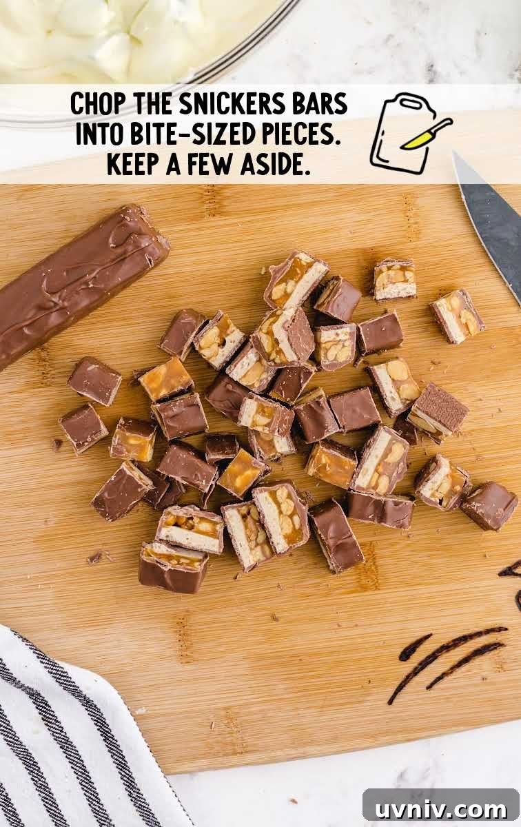 Snickers Salad Recipe: Creamy Dessert Salad with Chocolate & Peanut Butter 6 snickers bars being sliced on a wooden board