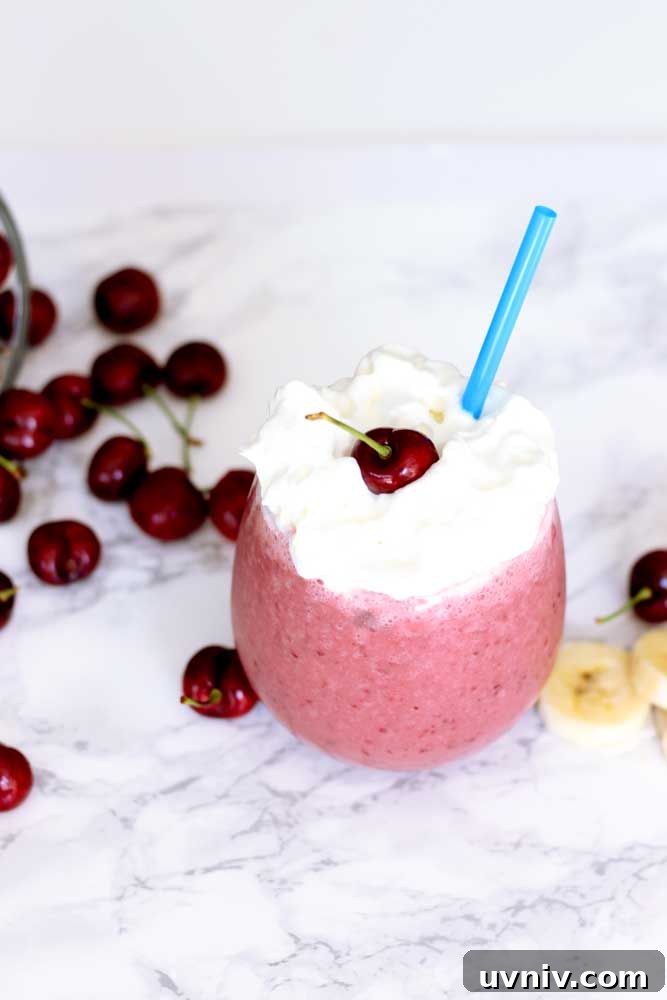 Creamy Cherry Banana Smoothie Recipe for Quick Energy 3 A close up of a cherry smoothie topped with whipped cream and a cherry.