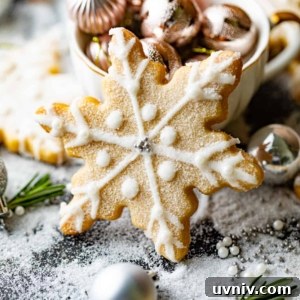 How to Make Perfect Snowflake Sugar Cookies for Winter Parties 11 a snowflake cookies in front of a tea cup filled with christmas ornaments.