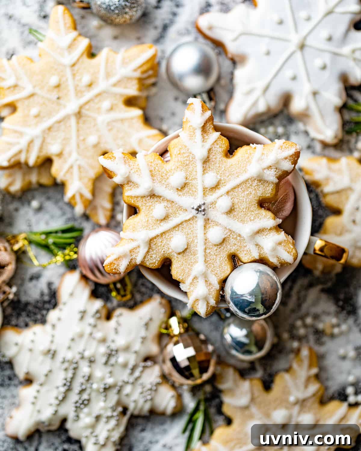 How to Make Perfect Snowflake Sugar Cookies for Winter Parties 3 snowflake cookies arranged on top of a wooden table.