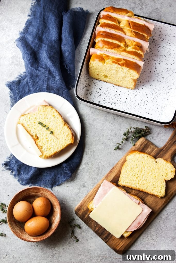 Ham and Cheese Breakfast Casserole Recipe for Brunch and Meal Prep 3 Ham and cheese sandwiched in between slices of brioche bread, eggs in a brown bowl, a wooden cutting board, a blue dish towel, and thyme.