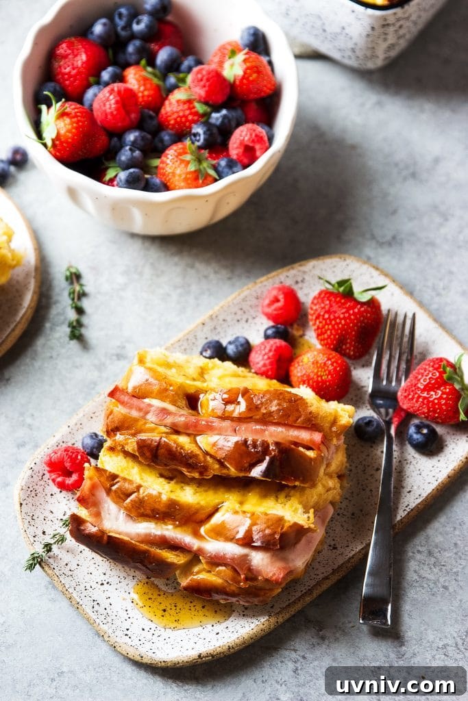 Ham and Cheese Breakfast Casserole Recipe for Brunch and Meal Prep 4 Ham and Cheese Breakfast Casserole served with warm syrup and a side of blueberries, strawberries and raspberries on a plate with a fork.