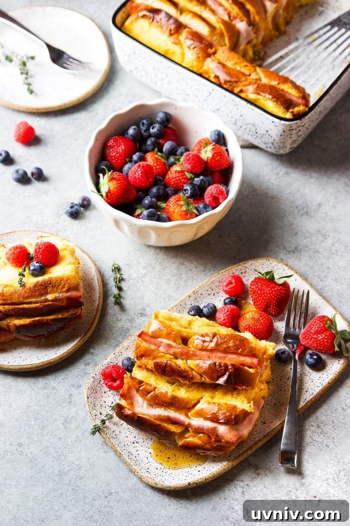 Ham and Cheese Breakfast Casserole Recipe for Brunch and Meal Prep 6 Ham and Cheese Breakfast Casserole served with warm syrup and a side of blueberries, strawberries, and raspberries on a plate with a fork, and fresh thyme.