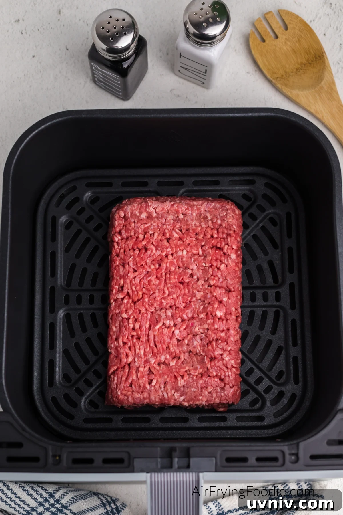 Ground beef in the basket of the air fryer ready to be broken up before cooking.