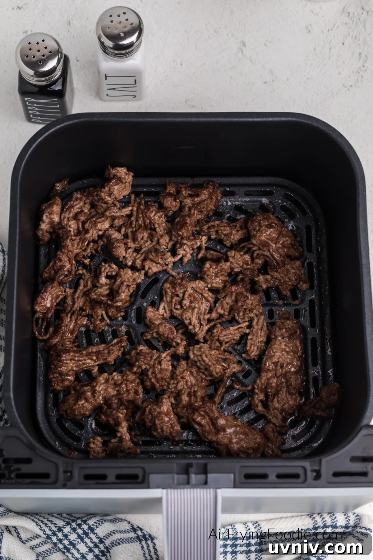 Air fried ground beef in basket of the air fryer, ready to season and serve.