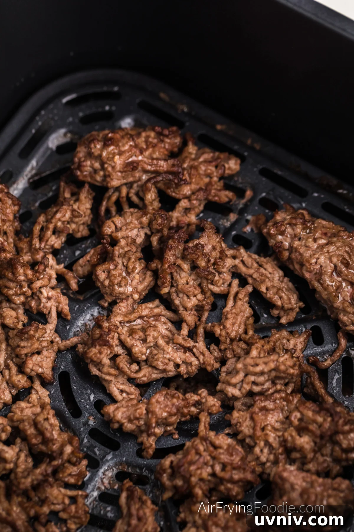 Close up photo of ground beef in the basket of the air fryer.