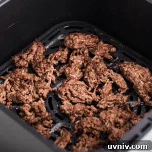 Crumbled ground beef in the basket of the air fryer, ready to serve.
