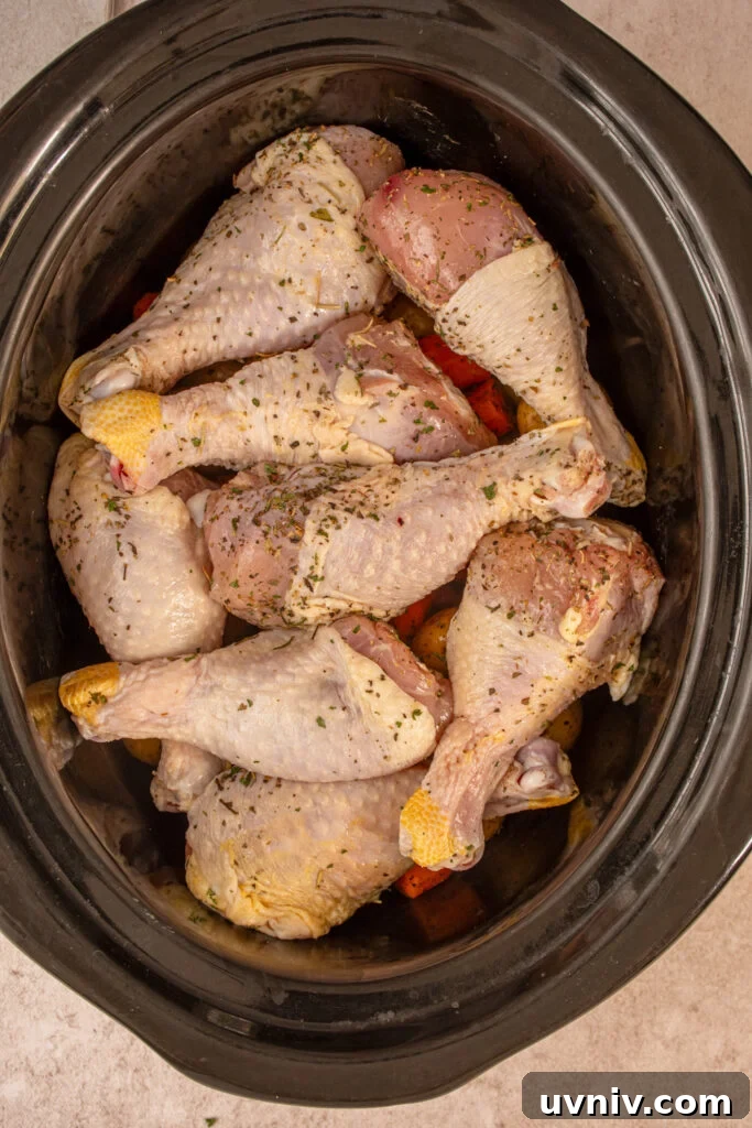 Slow Cooker Chicken Legs with Crispy Potatoes Recipe 8 The raw chicken legs on top of the vegetables ready to be cooked.