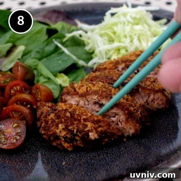 A pair of chopsticks taking a slice of Japanese menchi katsu.