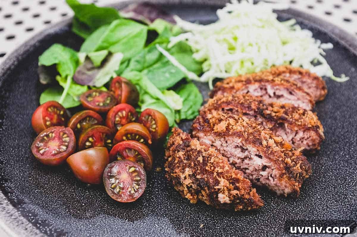 Menchi katsu and a small salad with shredded cabbage sit on a plate