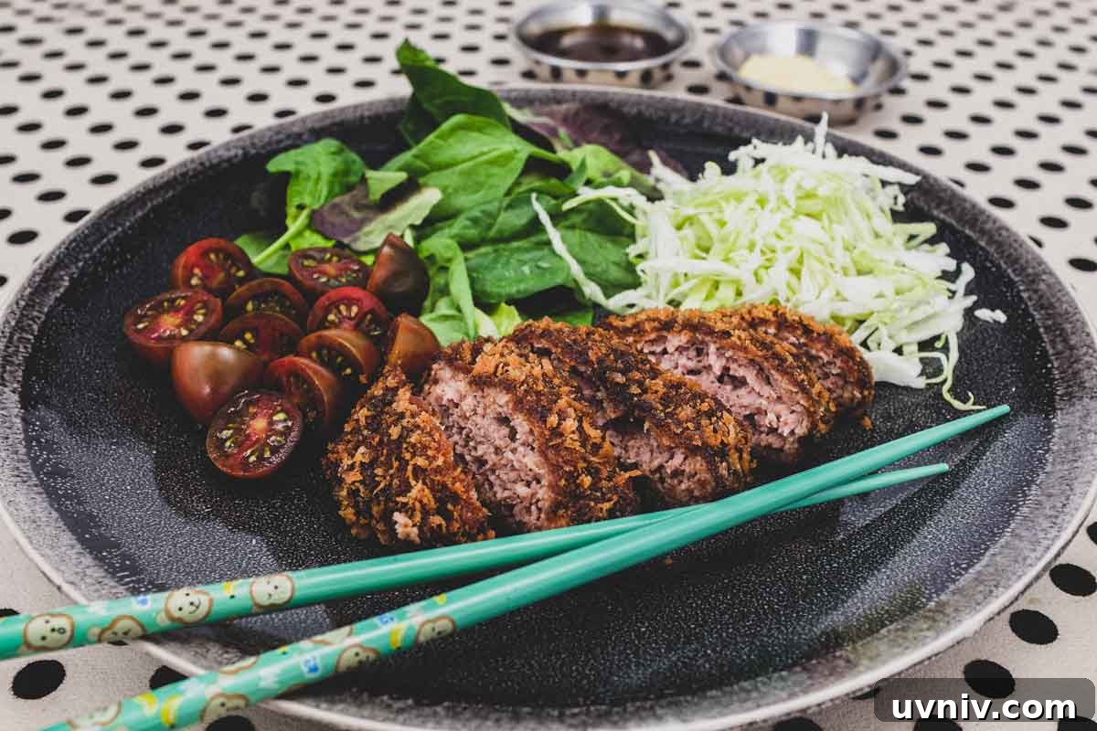 Menchi katsu and a small salad with shredded cabbage sit on a plate