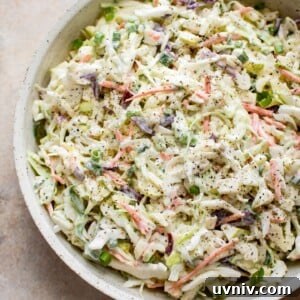 This simple apple slaw has cabbage, carrots, scallions, red and granny smith apples, and a tangy and sweet creamy dressing. This coleslaw recipe is great for pulled pork sandwiches!