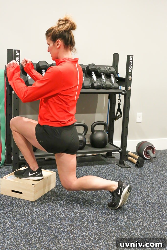 Effective At-Home Leg Workout Routine for Strength and Tone 5 Maryea Flaherty in a red jacket and black shorts completing a reverse lunge exercise with one foot on a brown box