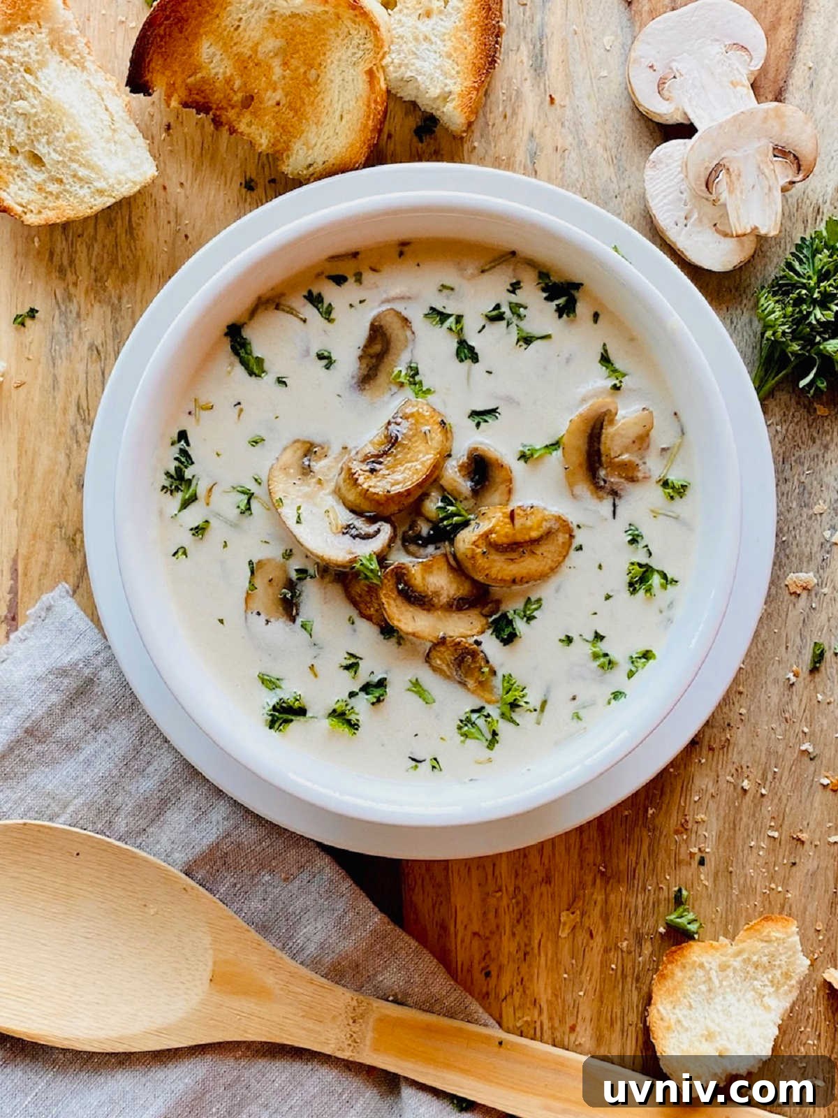 Creamy Wild Mushroom Soup Recipe — Comforting Homemade Soup 2 healthy mushroom soup in white bowl next to crusty bread