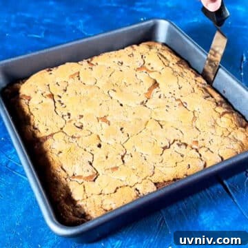 Brookie Recipe Using Brownie Mix: Chewy Cookie-Brownie Bars 11 Baked brownie cookie hybrid in baking pan with sides being loosened using an offset spatula.