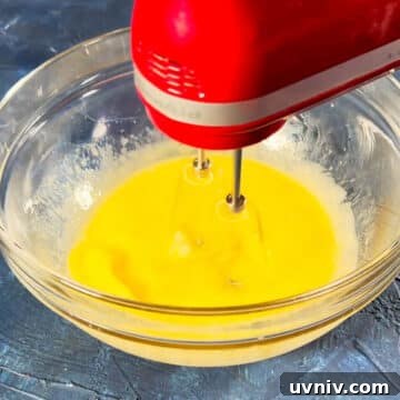 Brookie Recipe Using Brownie Mix: Chewy Cookie-Brownie Bars 5 Eggs, oil and water being mixed with a hand-held mixer in a glass bowl.