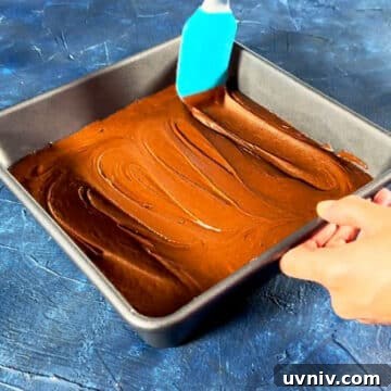 Brookie Recipe Using Brownie Mix: Chewy Cookie-Brownie Bars 9 Brownie batter being spread with rubber spatula in baking pan.