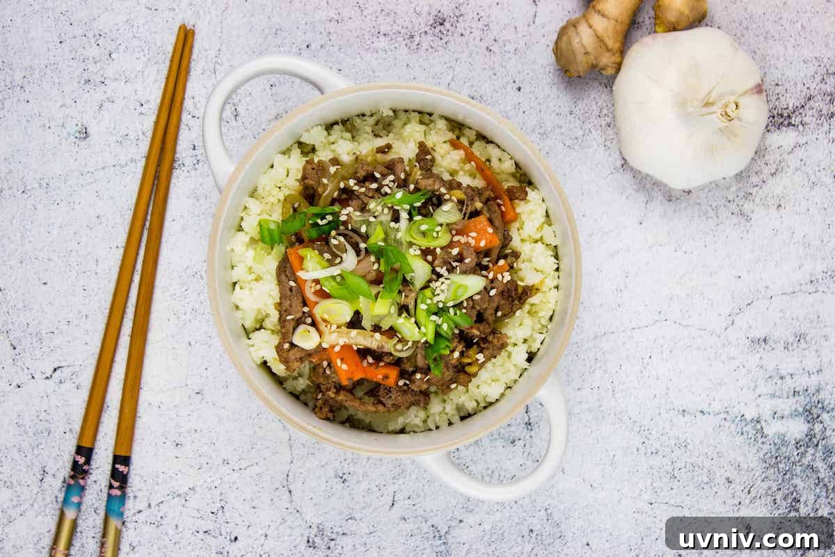 A top-down shot of Korean Beef Bowl with chopsticks, garlic, and ginger on the side.