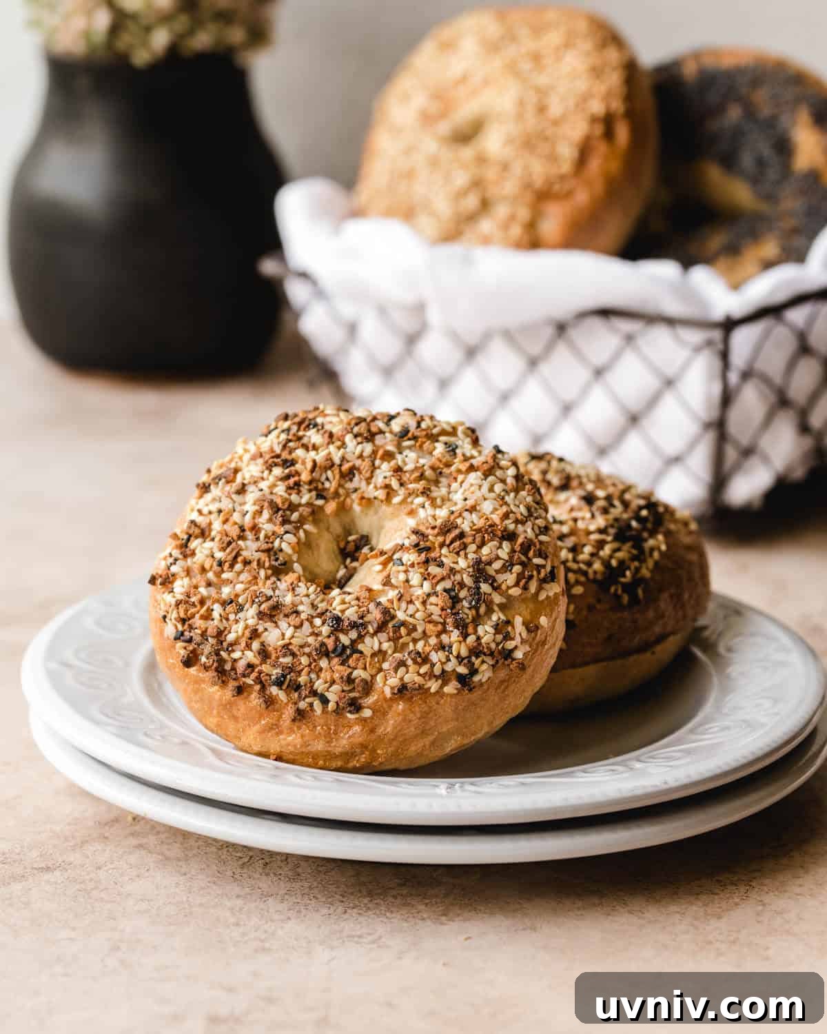 How Long Do Bagels Stay Fresh in the Fridge? 3 two bagels sitting on a small white plate in front of a basketful.