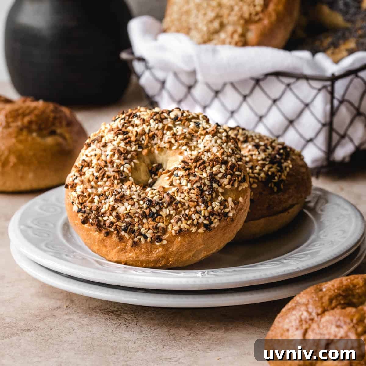 How Long Do Bagels Stay Fresh in the Fridge? 9 Two bagels laying on a plate with a basket of bagels behind it.